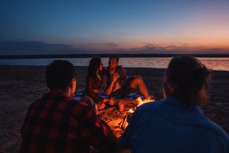 Friends having a bonfire on the beach at night